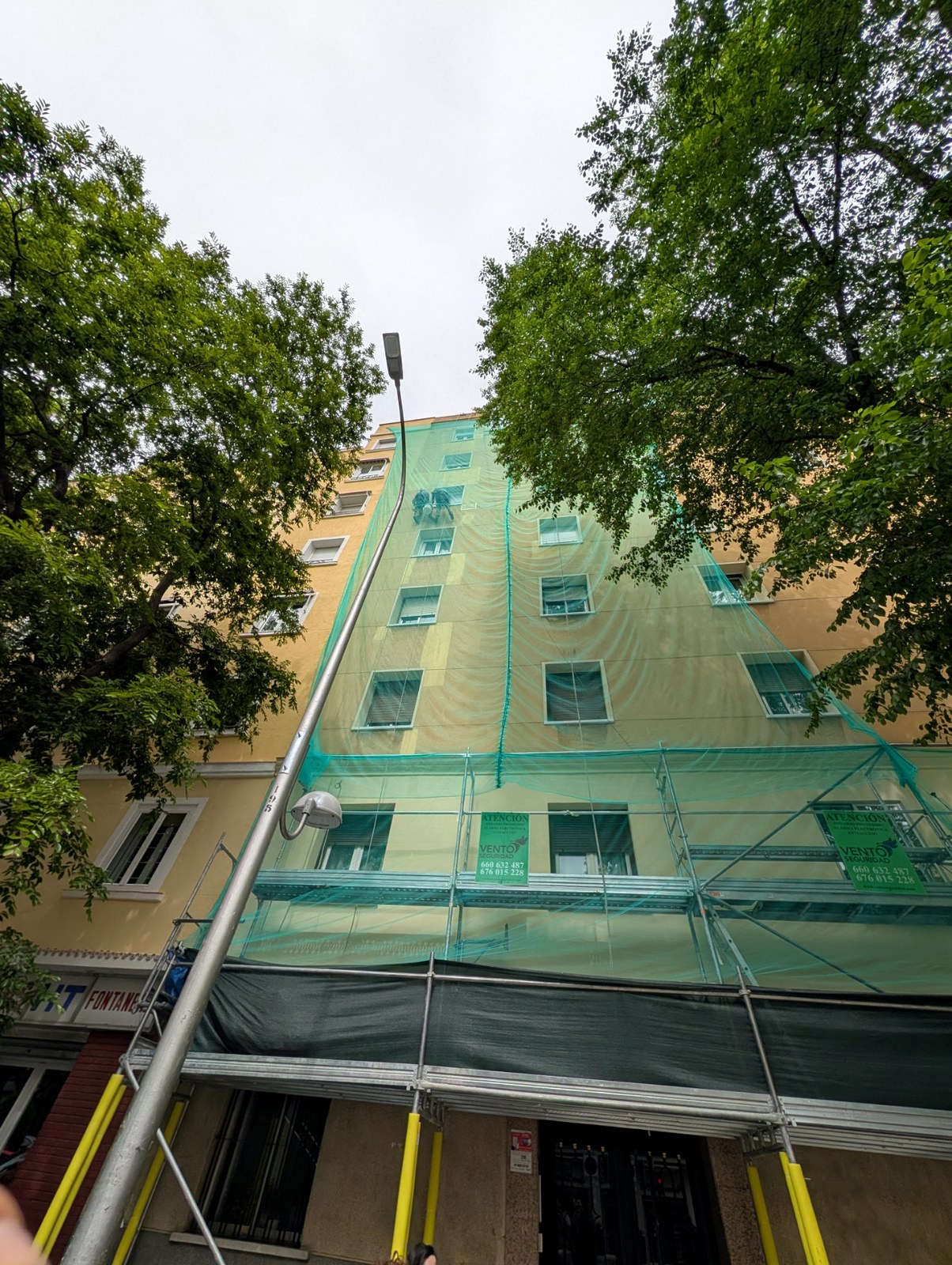 Operario de Grupo Illescas en cuerda con red de seguridad saneando fachada en altura